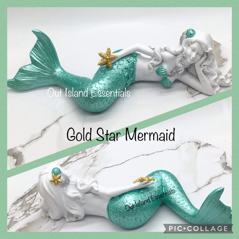 Pu&ograve; includere: Una statuetta di sirena bianca con una coda turchese e una stella dorata. La sirena &egrave; sdraiata di lato con la testa appoggiata sulla mano. La statuetta &egrave; su uno sfondo di marmo bianco. "Out Island Essentials" e "Gold Star Mermaid" sono scritti sull'immagine.