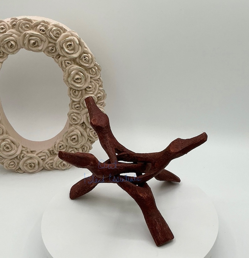 Op de afbeelding: Een houten standaard met drie poten, gemaakt van donkerbruin hout. De standaard is ontworpen om een kristal of ander object te houden.