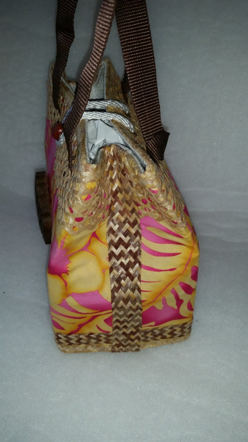 Puede incluir: Un bolso tejido marr&oacute;n y amarillo con un estampado floral rosa y correas marrones.
