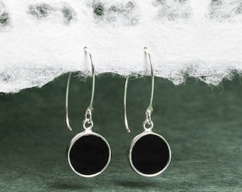 May include: A pair of silver dangle earrings with black round discs. The earrings have a simple design and are perfect for everyday wear.