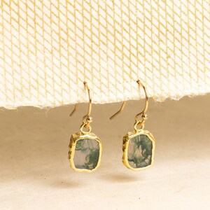May include: A pair of gold earrings with green agate stone accents. The earrings have a rectangular shape and a textured gold finish.