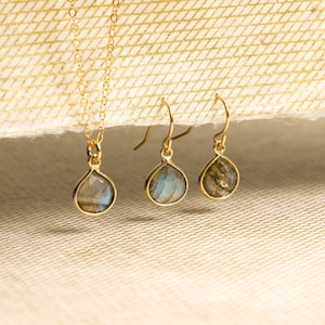May include: A set of gold-tone jewelry featuring a necklace and earrings with iridescent labradorite gemstone drops.