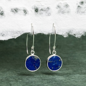 May include: A pair of silver dangle earrings with round blue lapis lazuli stones.