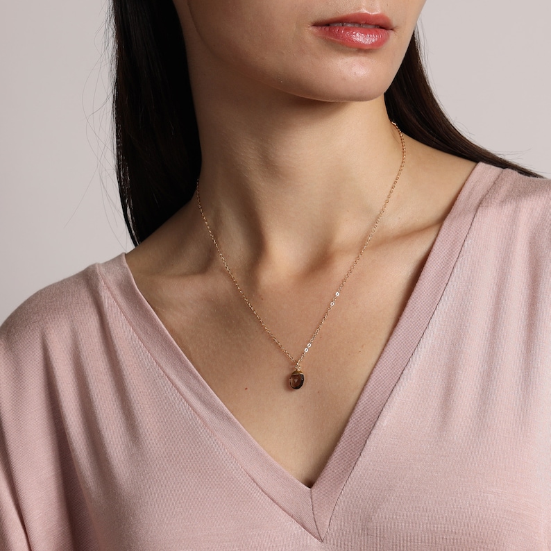 May include: A gold chain necklace with a small, round, brown gemstone pendant.