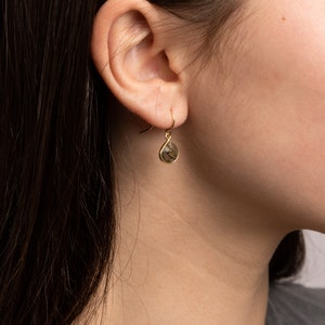 May include: Gold dangle earrings with a teardrop-shaped, dark gray gemstone.