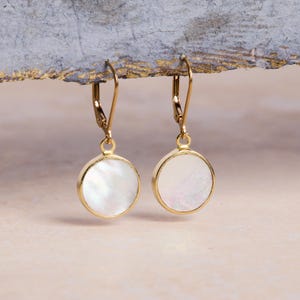 May include: A pair of gold earrings with white mother of pearl round discs.
