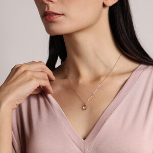 May include: A delicate gold chain necklace with a small, clear crystal pendant.