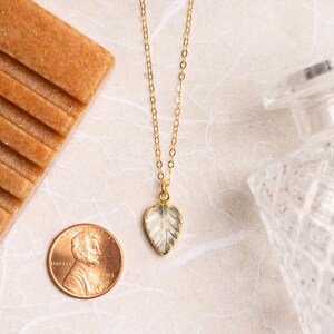 May include: A gold chain necklace featuring a clear, faceted leaf pendant. The pendant is heart-shaped and has a delicate, intricate design.
