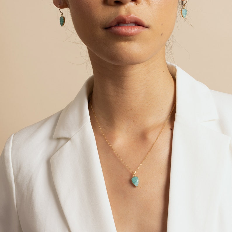 Puede incluir: Un collar de cadena dorada con un colgante turquesa en forma de l&aacute;grima. El colgante tiene una superficie texturizada.