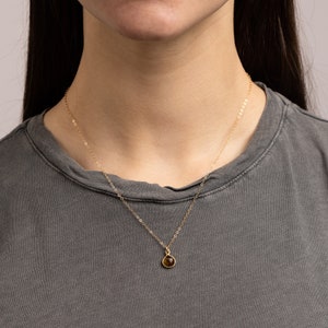 May include: A gold chain necklace with a small, teardrop-shaped brown gemstone pendant.