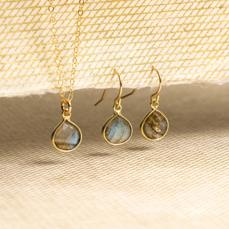 May include: A set of gold-tone jewelry featuring a necklace and earrings with iridescent labradorite gemstone drops.