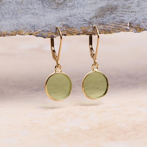 May include: A pair of gold dangle earrings with light green round glass stones.