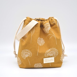 May include: Mustard-coloured drawstring bag with a white floral pattern. The bag has a cream-coloured strap and drawstring cords. A small rectangular label with the text "LuSi" is on the front.