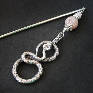 Può includere: Bastoncino per capelli in argento con una perla di agata rosa e un ciondolo a forma di serpente in argento. Il serpente è avvolto e ha una superficie testurizzata.