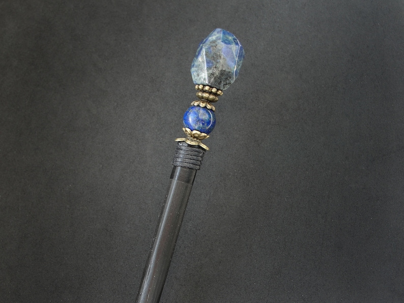 May include: A black wooden hair stick with a blue lapis lazuli gemstone and gold accents.