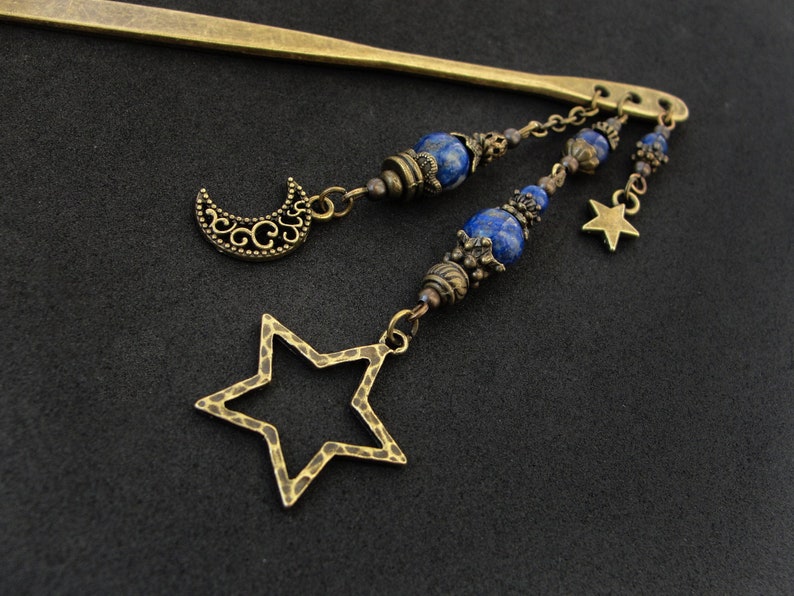 Puede incluir: Una varita para el pelo dorada con un dije de luna creciente y un dije de estrella. La varita est&aacute; decorada con cuentas azules de lapisl&aacute;zuli y detalles dorados.