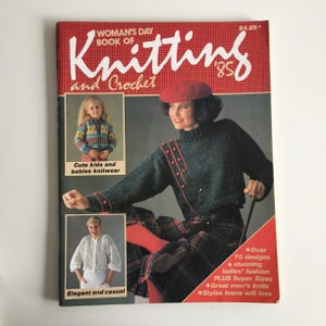 May include: A vintage "Woman's Day Book of Knitting and Crochet" magazine from 1985. The cover features a woman in a green sweater and plaid skirt, and two smaller photos of knitwear. Text includes "Cute kids and babies knitwear" and "Elegant and casual".