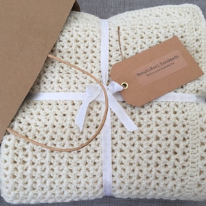 May include: A white crocheted blanket wrapped in brown paper with a white ribbon and a brown tag that reads "BeautiWool Handmade Melbourne Australia".