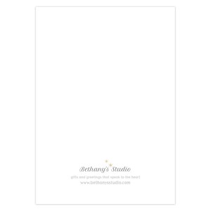 May include: White card with the text "Bethany's Studio" in black script font. Below the text is the phrase "gifts and greetings that speak to the heart" in a smaller font. Below that is the website address "www.bethanystudio.com" in a smaller font.