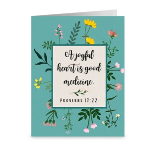 Peut inclure: Une carte bleu turquoise avec un cadre blanc et une bordure florale. Le texte à l'intérieur du cadre dit "Un cœur joyeux est une bonne médecine. Proverbes 17:22".