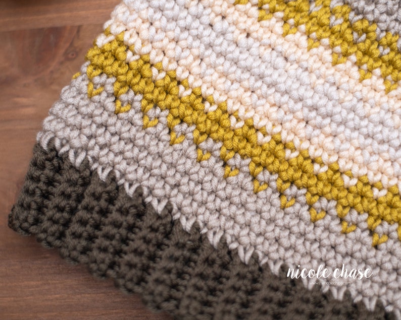 Pode incluir: Close-up de um chap&eacute;u de croch&ecirc; com listras de fio bege, creme e amarelo mostarda. O chap&eacute;u tem uma borda de croch&ecirc; marrom escura.