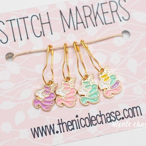 May include: Set of four gold stitch markers with unicorn charms. The charms are pink, purple, green, and yellow with white details. The card reads "Stitch Markers" and "www.thenicolechase.com".