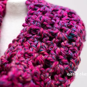 K&ouml;nnte beinhalten: Nahaufnahme eines geh&auml;kelten Kragens in Pink, Blau und Lila. Der Kragen ist mit einem strukturierten Stich gearbeitet und hat einen weichen, flauschigen Look.