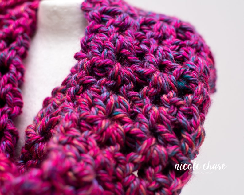 K&ouml;nnte beinhalten: Nahaufnahme eines geh&auml;kelten Kragens in Pink, Blau und Lila. Der Kragen ist mit einem strukturierten Stich gearbeitet und hat einen weichen, flauschigen Look.