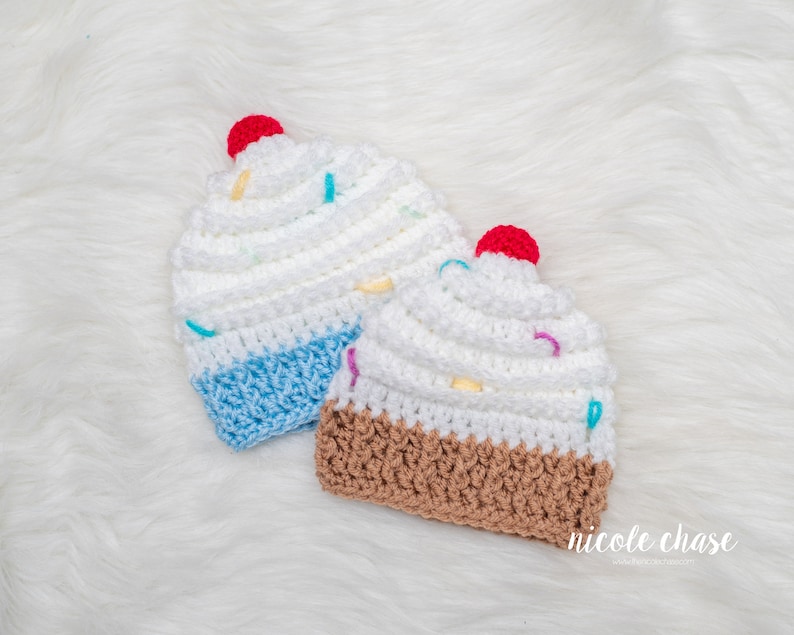 Peut inclure: Deux bonnets en crochet en forme de cupcake, l'un avec du gla&ccedil;age bleu et l'autre avec du gla&ccedil;age brun. Les deux bonnets ont du gla&ccedil;age blanc et des p&eacute;pites color&eacute;es.