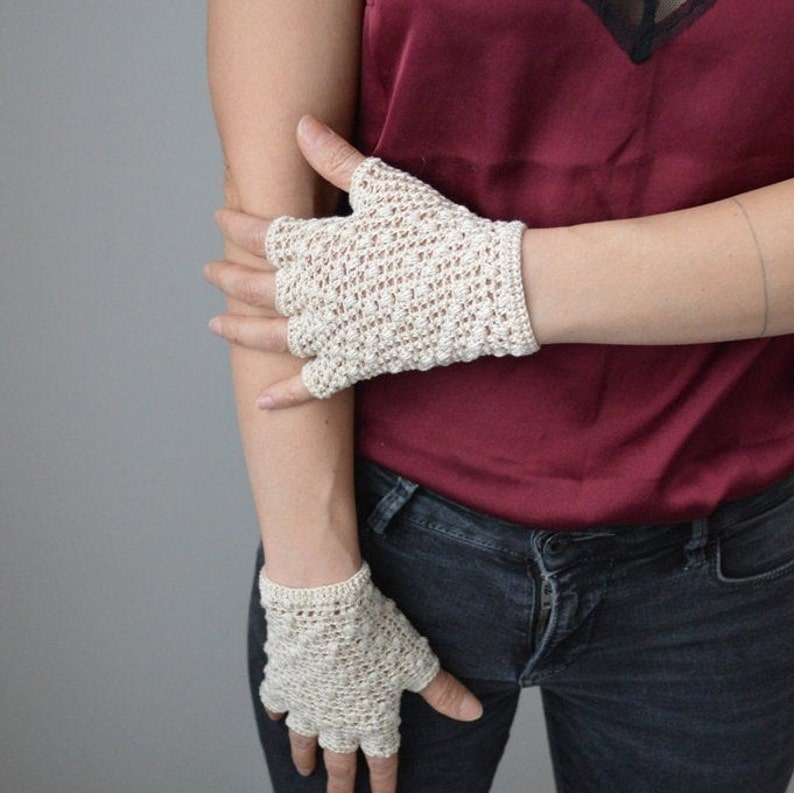 Peut inclure: Une paire de mitaines sans doigts en crochet de couleur blanc cass&eacute;. Les mitaines ont un design d&eacute;licat et ajour&eacute;.