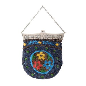 May include: A vintage beaded purse with a silver-tone frame and chain handle. The dark blue purse features a floral design in a circular pattern with red, yellow, and blue flowers. The purse is covered in small, colorful beads.