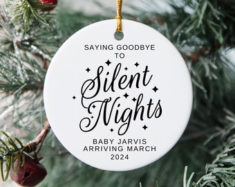 May include: White round Christmas ornament with black text that reads "Saying goodbye to Silent Nights. Baby Jarvis arriving March 2024".