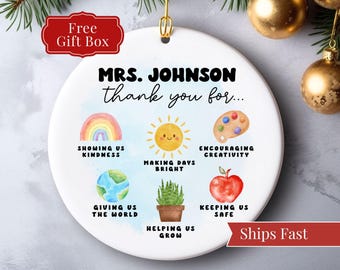 Könnte beinhalten: Weißes Keramikornament mit goldener Aufhängeschlaufe. Das Ornament zeigt den Text "MRS. JOHNSON thank you for..." und farbenfrohe Illustrationen eines Regenbogens, einer Sonne, eines Globus, einer Farbpalette, einer Pflanze und eines Apfels. Die Wörter "Free Gift Box" und "Ships Fast" sind ebenfalls vorhanden.