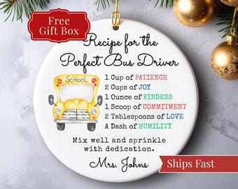 May include: White ceramic ornament with a gold hanging loop. The ornament features a yellow school bus illustration and text that reads "Recipe for the Perfect Bus Driver." Includes the text "Free Gift Box" and "Ships Fast."
