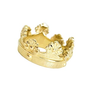 May include: A gold crown ring featuring a detailed floral design. The ring is crafted from solid gold and has a polished finish.