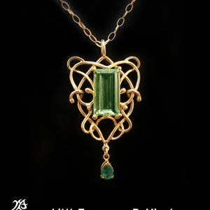 May include: A gold pendant necklace featuring a green gemstone set within a Celtic knot design. The pendant has a teardrop-shaped green gemstone dangling from the bottom.