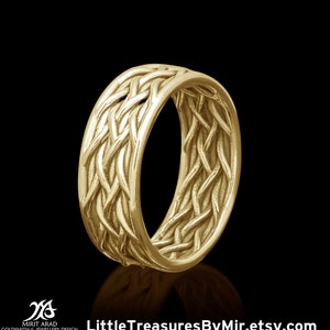 Könnte beinhalten: Ein goldener geflochtener Ehering mit einem gewebten Design. Der Ring ist dick und hat eine polierte Oberfläche.