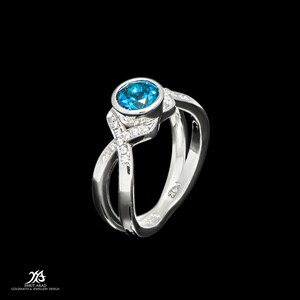 May include: A white gold ring with a blue gemstone and small diamonds set in the band.