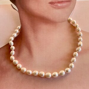 May include: A simple white pearl necklace with a classic design. The necklace is made of smooth, round pearls that are strung together on a delicate chain.