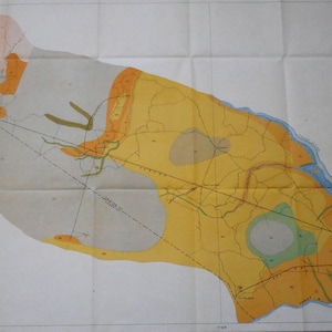 May include: A vintage map with a detailed, colorful geological layout. The map features shades of yellow, orange, green, and blue, with various lines and symbols indicating geographical features. The map is folded and appears to be aged.