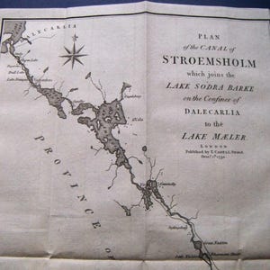 May include: An antique map titled "Plan of the Canal of Stroemsholm" showing the canal's route and surrounding lakes. The map, printed in black ink, includes a compass rose and text detailing the canal's connection to Lake Mæler.