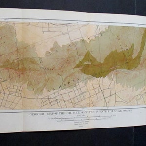 May include: A vintage geologic map of the oil fields of the Puente Hills, California. The map features a detailed illustration with various colors, including shades of green, brown, and beige, and grid lines. The title and other text are visible at the top and bottom.