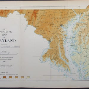 May include: A vintage hypsometric map of Maryland, including Delaware and the District of Columbia. The map features a color-coded elevation scale and detailed geographical features. The map is printed on aged paper and includes text such as "Maryland Geological Survey".