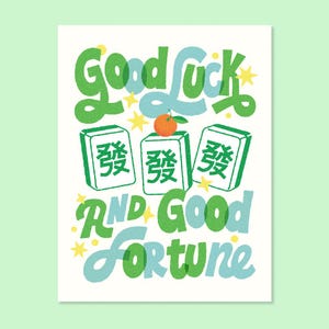 Puede incluir: Una impresión blanca con las palabras "Good Luck and Good Fortune" en verde y azul, con acentos de estrellas amarillas. La imagen incluye tres fichas de Mahjong verdes y una pequeña fruta naranja.