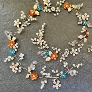 May include: Gold floral hair vine with white pearls and orange, pink, and teal colored flowers. The vine is flexible and can be worn in a variety of styles. A matching gold comb with teal and orange flowers is also included.