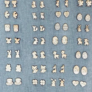 May include: A collection of wooden earrings featuring various designs, including animals, hearts, eggs, and religious symbols. The earrings are all made of natural wood and have a rustic, handmade look.
