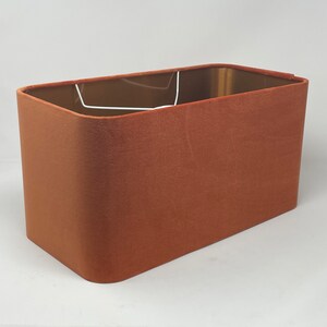 May include: A rectangular lampshade made of a rust-coloured velvet fabric.