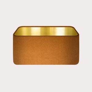 May include: A brown rectangular box with a gold top. The box is made of a textured material and has a slightly rounded edge.