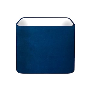 May include: A square, navy blue lampshade with a white interior. The lampshade has rounded corners and a smooth, velvety texture. The open top allows light to shine through.