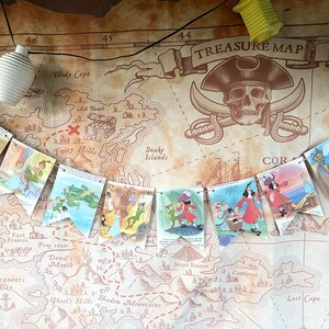 K&ouml;nnte beinhalten: Ein farbenfroher Papierbanner mit Illustrationen von Figuren aus Peter Pan. Der Banner ist an einer schwarzen Schnur befestigt und h&auml;ngt vor einem braunen Hintergrund mit einer darauf gedruckten Schatzkarte. Die Karte zeigt einen Totenkopf mit gekreuzten Knochen und die Worte "TREASURE MAP".